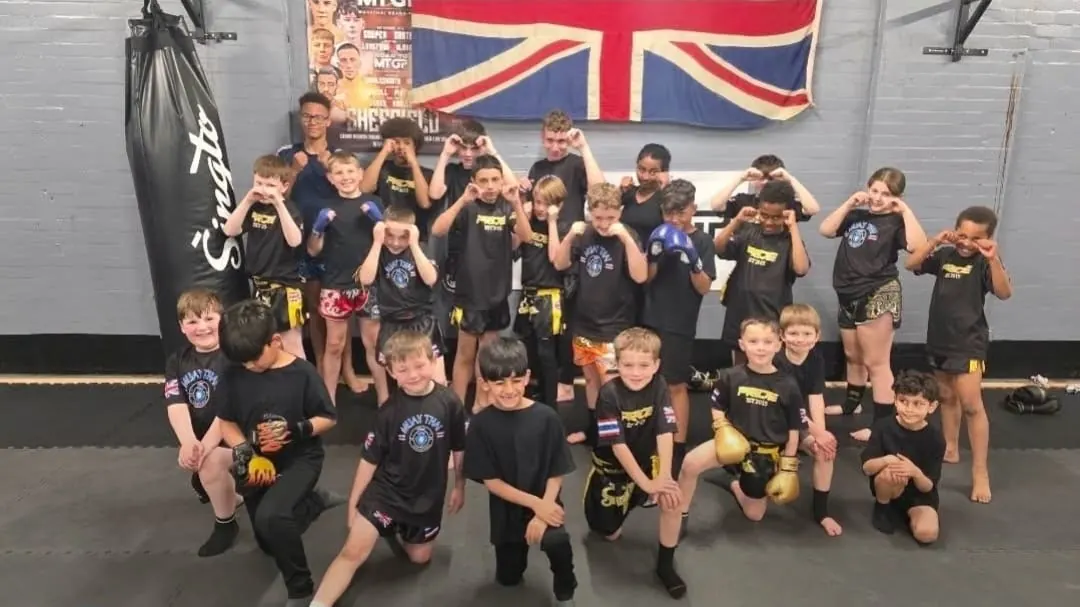Pride Gym Sheffield kids and junior Muay Thai team posing together under the Union Jack in the gym